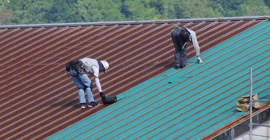 職人が屋根の上でカバー工法の作業をしている様子